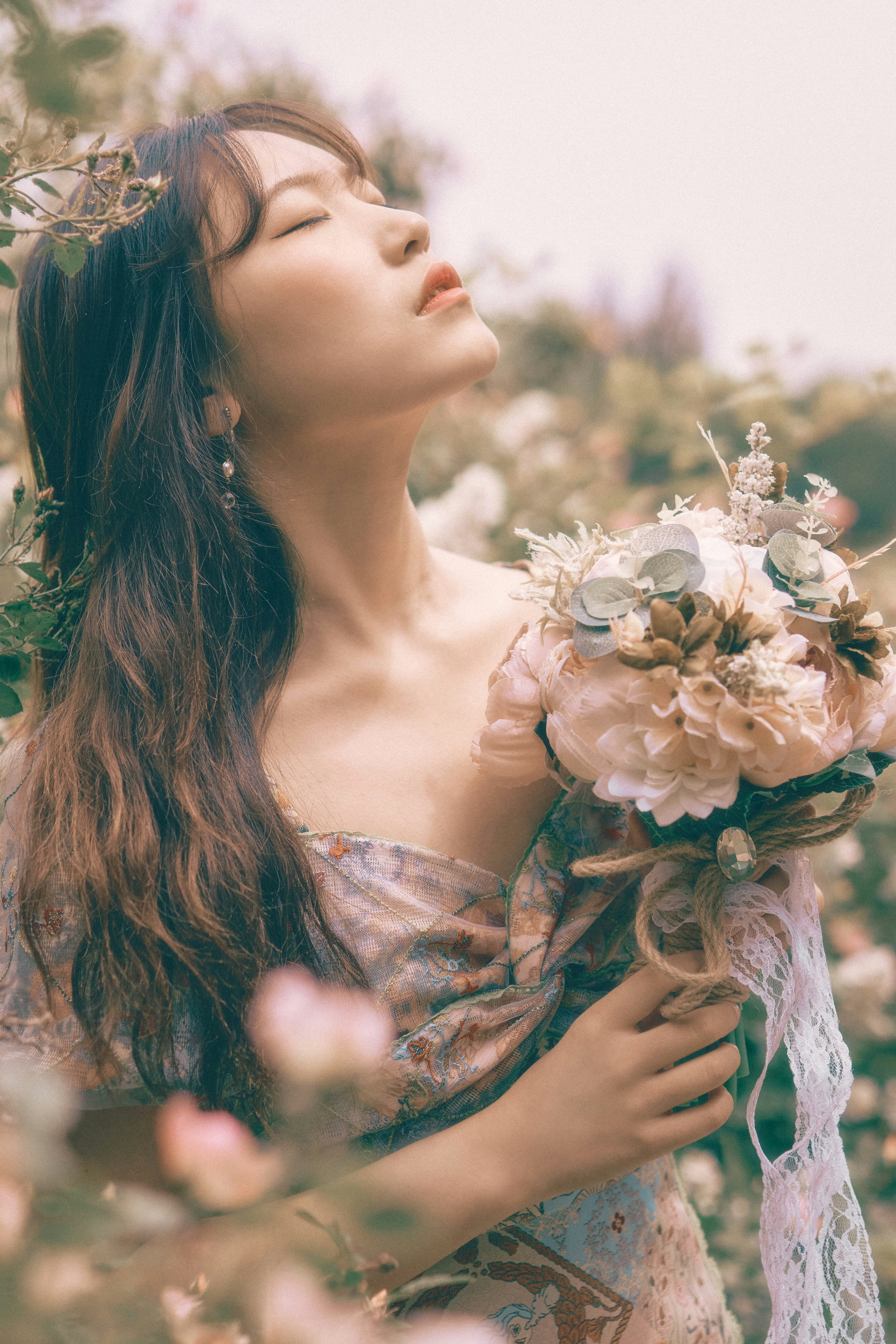 woman in brown and white floral dress holding white flowers